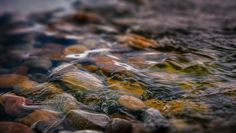 Close up of water rushing over pebbles and stones in a creek