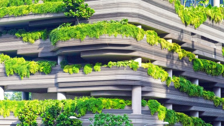a high rise concrete parking lot with greenery growing all over it