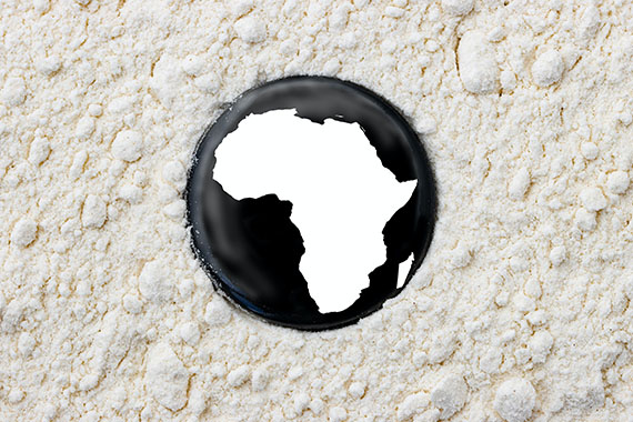 A polished button with a map of the African continent lies on some white sand